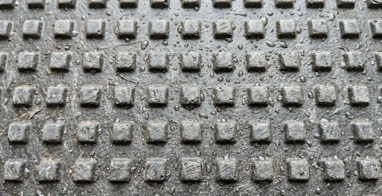 Plan macro rapproché montrant la texture granuleuse d'une surface en fibre de verre avec de fines gouttes d'eau perlant sur le relief antidérapant