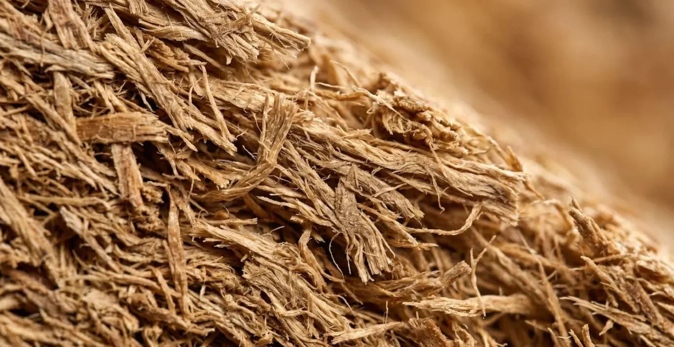 Détail macro de la structure fibreuse dense d'un panneau d'isolation en fibre de bois révélant sa capacité d'inertie thermique