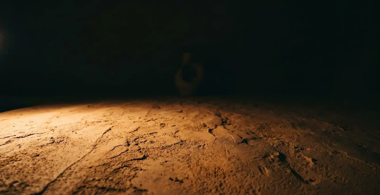 Mur en terre crue sublimé par un éclairage rasant créant des ombres dramatiques